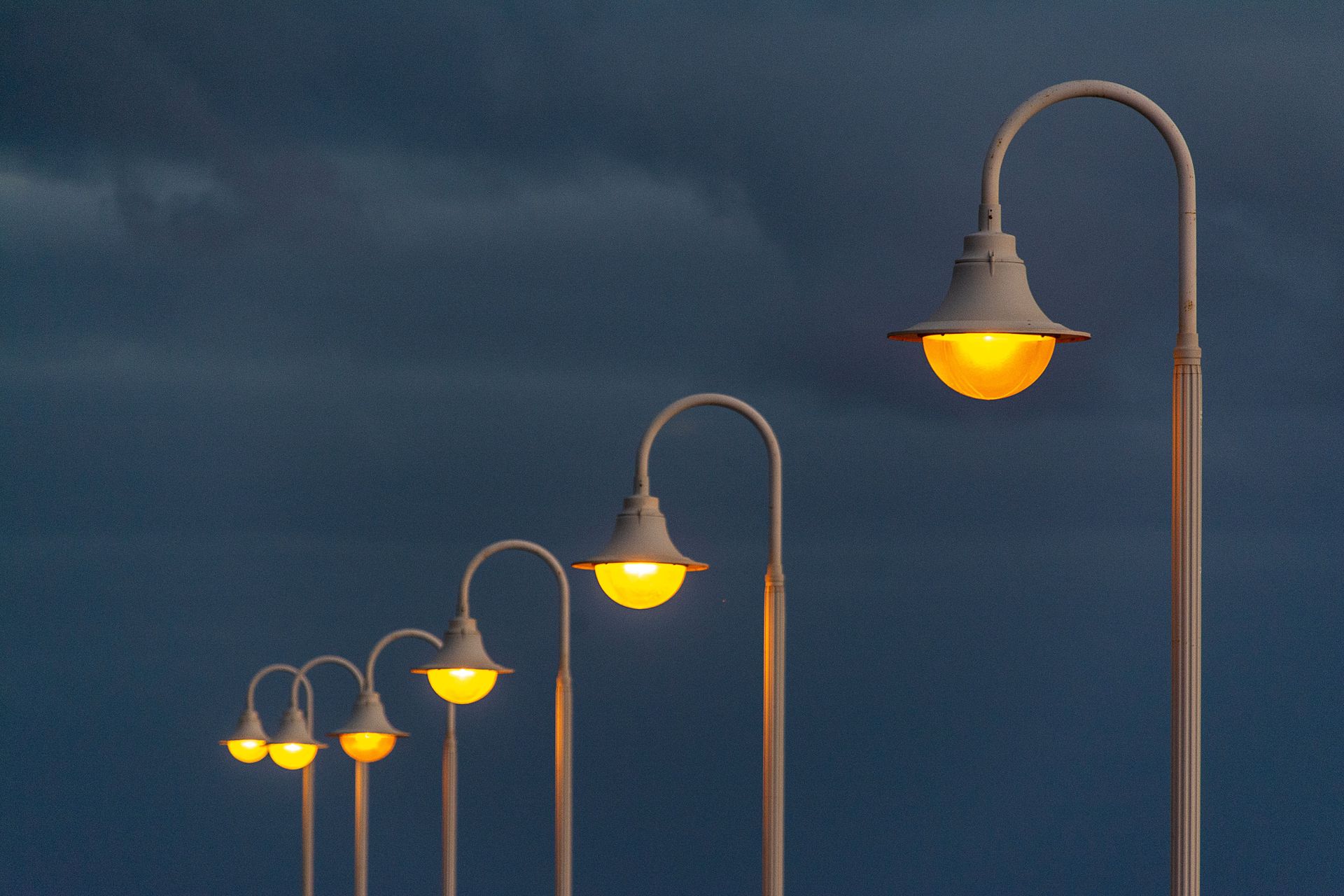 Aesthetic view of street lamps glowing against a dark evening sky.